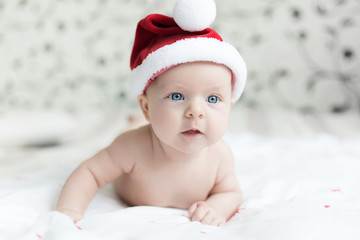 Little baby girl in red Santa hat is wondering what will be A Christmas