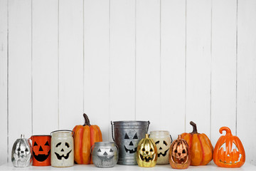 Halloween decor display of Jack o Lantern candle holders on a shelf against a rustic white wood...