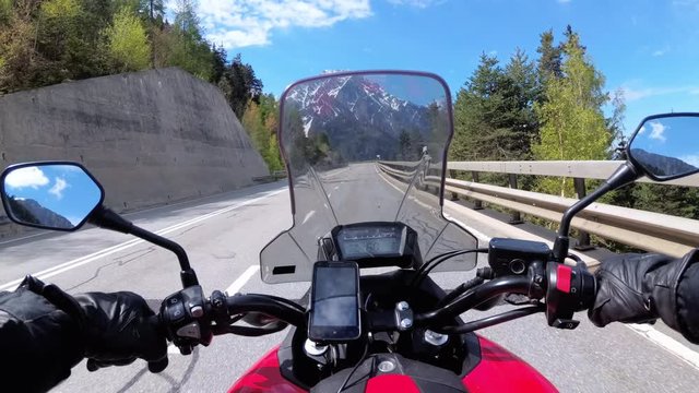 Motorcyclist Rides on Beautiful Landscape Mountain Road near Snowy Switzerland Alps
