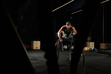 Inflated man performs an exercise with ropes, view from the side of the ropes