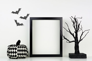 Mock up black frame with pumpkin and spooky tree decor on a shelf or desk. Halloween concept....