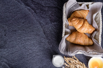 Fototapeta na wymiar fresh croissants in a basket with a black slate background, top view.