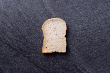 Bread slice on black slate background. Top view Copy space