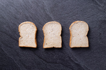 Bread slice on black slate background. Top view Copy space
