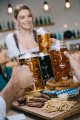 cropped view of multicultural friends clinking mugs of light and dark beer