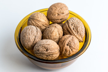 Walnuts in a yellow bowl isolated on white, top view