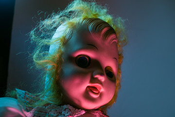 Scary old doll under dramatic light