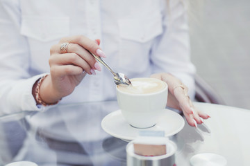 Close-up of woman's hands holding spoon and drinking coffee