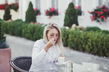 Stylish woman in the cafe sits at a table, drinks coffee 
