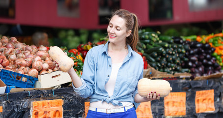 Portrait of woman who is choosing pumpkin in the market.