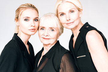 portrait of elegant three-generation blonde women in total black outfits isolated on grey