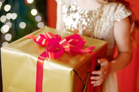 Beautiful little girl holding a Christmas gift box. Christmas and New Year celebration concept. Winter holidays. Closer up picture