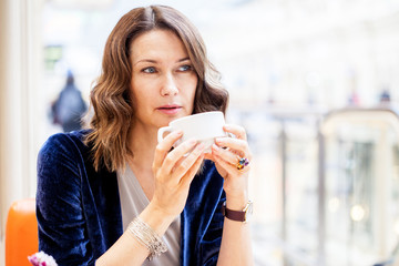 A beautiful middle-aged woman with a white cup of coffee in her hands