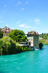 Fototapeta na wymiar Historical buildings along turquoise Aare River in the historical old town of the Swiss capital Bern. Switzerland summer, city. Captured on a vertical picture on a sunny summer day