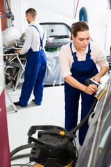 Female mechanic preparing automobile for painting