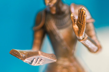 Closeup of the hand of a bronze statue holding an open book and another hand up. Sculpture close...
