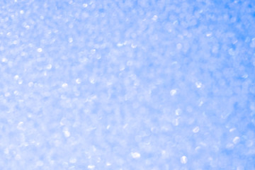 Soft focus bokeh light effects over a rippled, blue water background with lens flare.