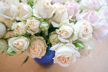A bouquet of fresh tea and gently pink roses on a beige background.