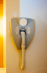 Detail of hairdryer hanged on the wall of bathroom in modern hotel with power plug for the razor machine