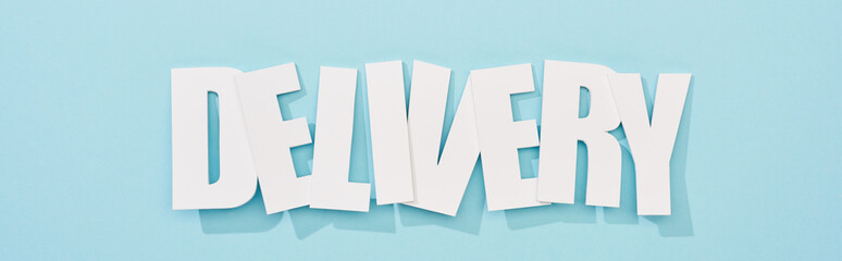 panoramic shot of crooked white delivery inscription on blue background