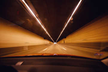Perspective view from the car at the long orange tunnel with end at the end - fast transportation in modern futuristic city