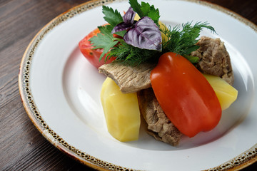 Boiled meat with a side dish and vegetables . restaurant menu