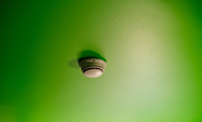 White smoke detector on the green roof in modern luxury hotel apartment office building