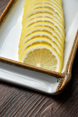 Thin sliced lemon on a brown wooden background. restaurant menu