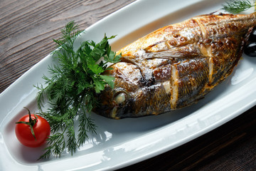 Grilled fish with a side dish and vegetables. restaurant menu