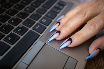 Females hands with manicured nails working on a modern laptop