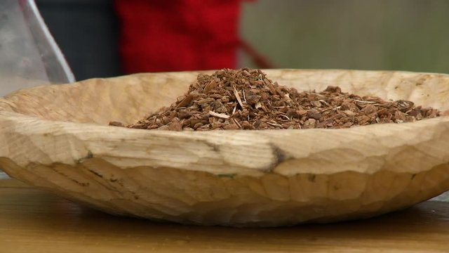 Steady, close up shot of a wooden bowl full of cramp bark.