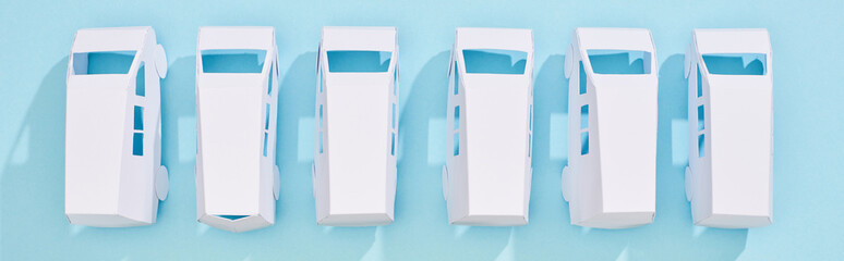 panoramic shot of white miniature autos on blue background