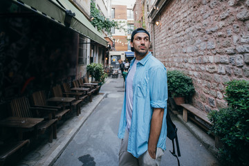 Fototapeta na wymiar A man tourist walks through the streets with a backpack