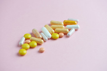 Vitamins on pink paper background. Concept for a healthy dietary supplementation. Close up. Copy space. 