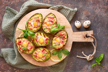 Top view on grilled avocado boats with bacon and quail eggs, fla