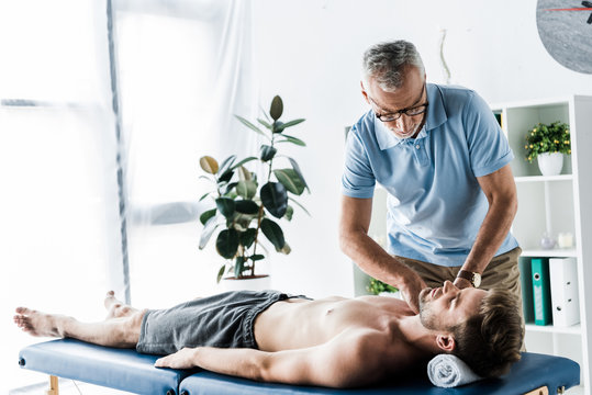 Bearded Chiropractor Doing Massage To Handsome Man On Massage Table