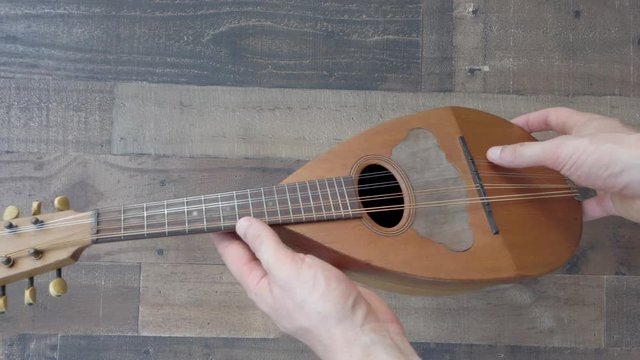 Male hands holding uke inspect it isolated over brown wood background, flat lay.