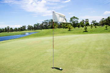 Obraz premium White flag at the golf course of on green with blue sky, Asia Bangkok Thailand.