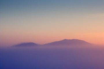 Minimalistic winter landscape. Mountain peaks above the frosty fog. Amazing sunset. Cold winter weather. Majestic Arctic scenery. Mount Dionysius, Chukotka, Far East Russia. Perfect for background.