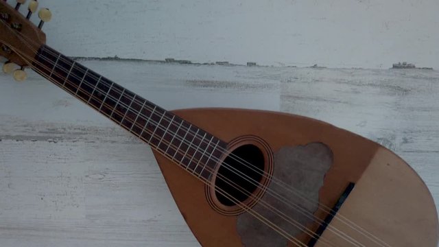 Panning over small uke instrument, top down, 4k on white wooden background.