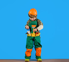 Work with tools. Little boy in builder's uniform with repair tools. Repair. Boy as builder or repairer. Tools for building. Builder boy in helmet and tools. Little repairman with tool  Child game.