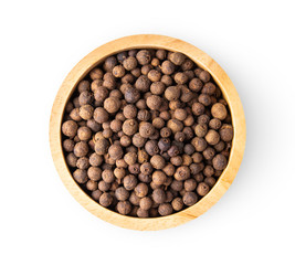 Allspice berries (also called Jamaican pepper or newspice) in wood bowl on white background. top view