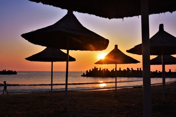 sunlight through umbrellas on the beach at sunrise