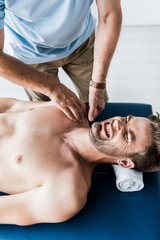 overhead view of chiropractor doing massage to man with closed eyes suffering pain
