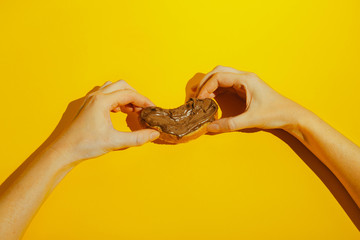 hands holding bread slices spread with chocolate on a yellow background