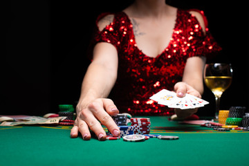 Casino games. A girl in a red evening dress and plays poker in a night casino. opens cards and takes winnings