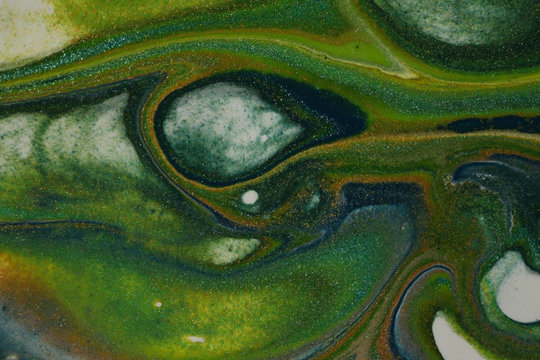 Flowing abstract acrylic pour painting in dark blue,  neon green, glitter teal, glitter gold, with contrasting white cells for backgrounds.