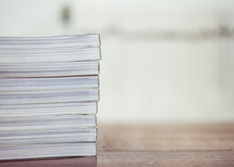 selective focus  of stack of magazine on wooden table  with blurred book shelf  background
