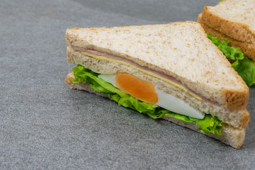 Homemade sandwich or toast wheat bread with lettuce and ham on the concrete table.