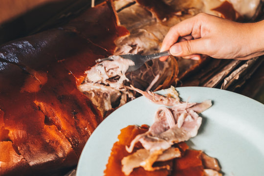 Hand getting a piece of the popular and delicious roasted pig or "lechon baboy"  using fork. Selective focus.